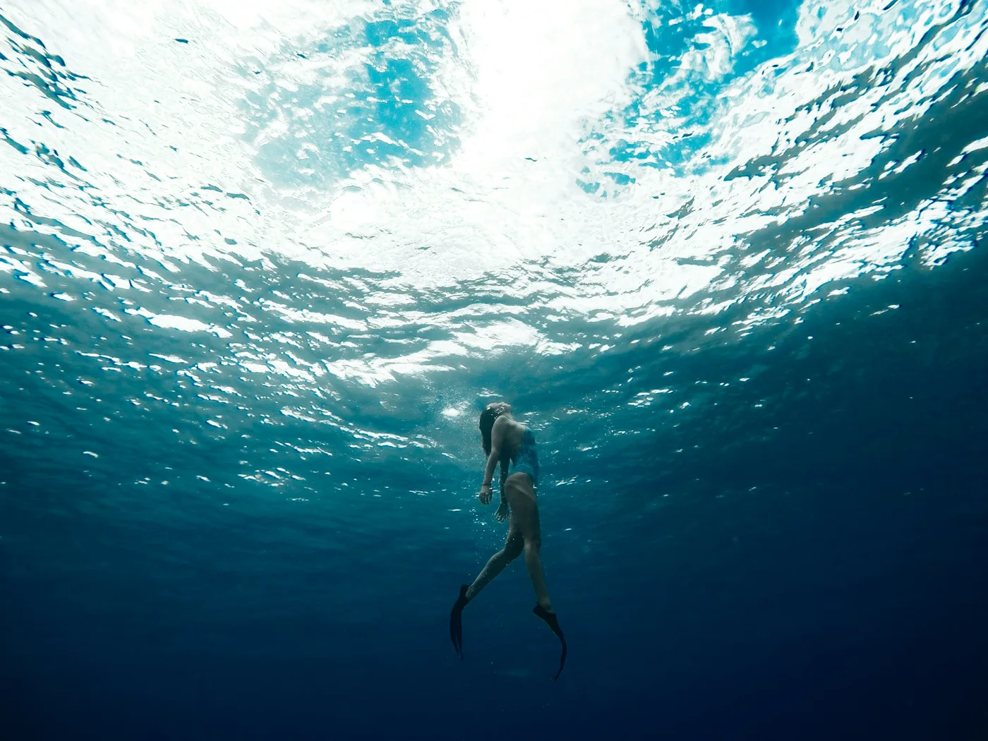 Un subacqueo che si immerge scendendo attraverso acque azzurre e cristalline